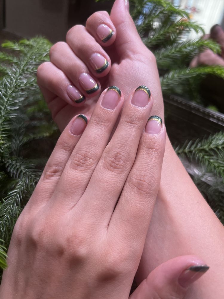 Green and gold French tip manicure, close-up on two hands