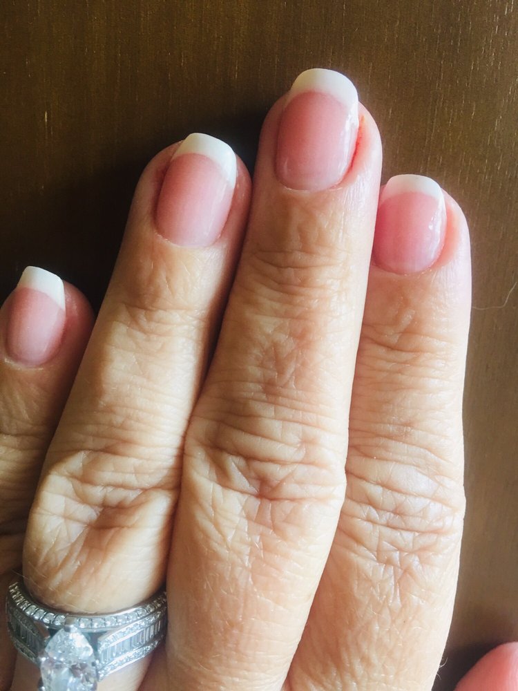 Classic white French manicure on a warm wood background, Glamour Nails Seattle