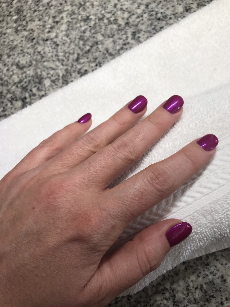 Glossy magenta gel manicure resting on a marble counter